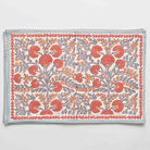A rectangular placemat with a floral pattern featuring periwinkle vines and warm orange blooms.