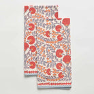 A set of two white kitchen towels with a floral pattern featuring periwinkle vines and warm orange blooms.