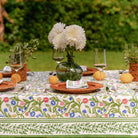 A colorful floral tablecloth with yellow, blue, and red flowers displayed on a table outdoors.