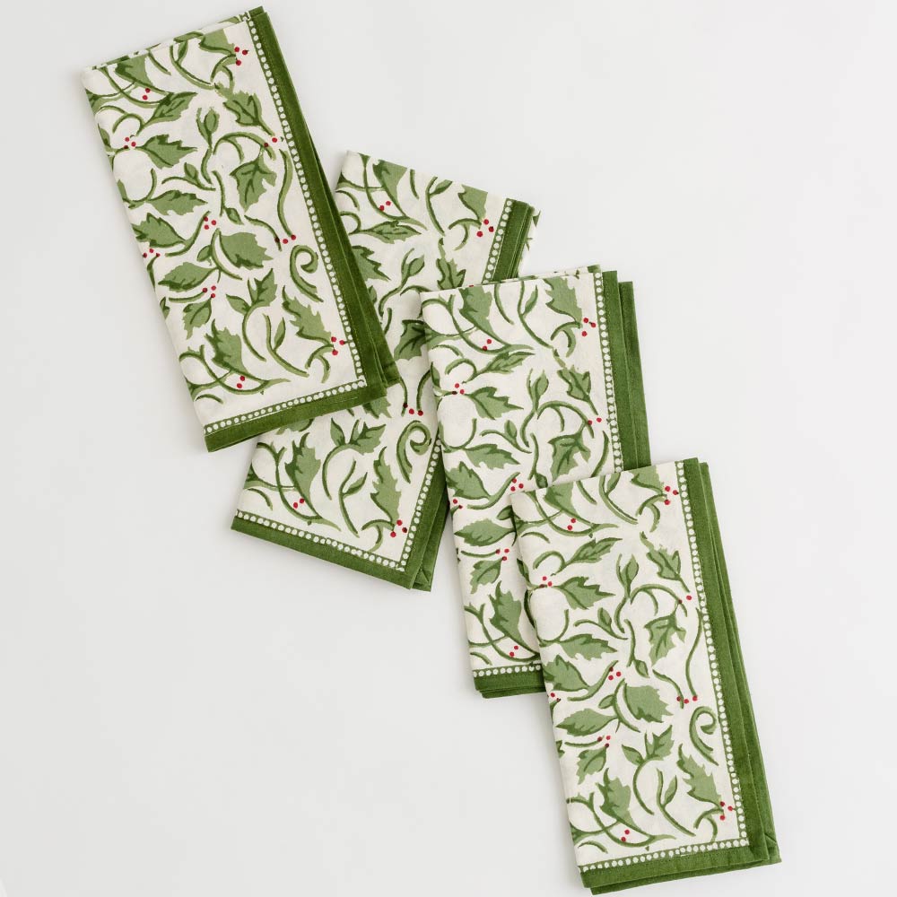 A set of 4 holly berry printed napkins on a white background
