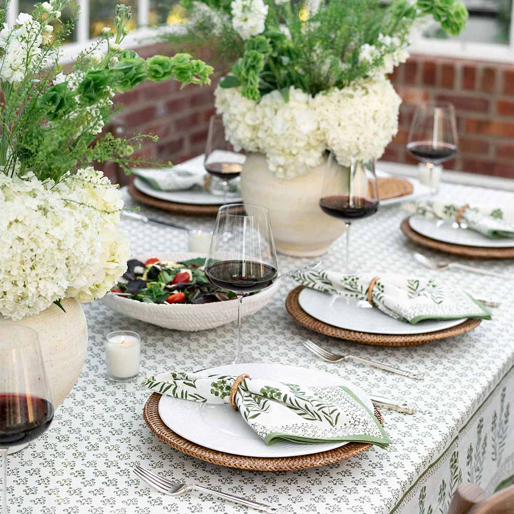 Tablecloth with matching napkins, food, flowers, and wine.