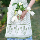 Model wearing apron and holding flowers.