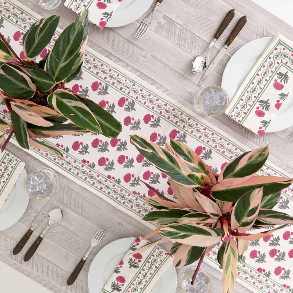 Table runner and plant centerpieces with matching napkins on dinner plates. 