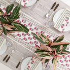 Table runner and plant centerpieces with matching napkins on dinner plates. 