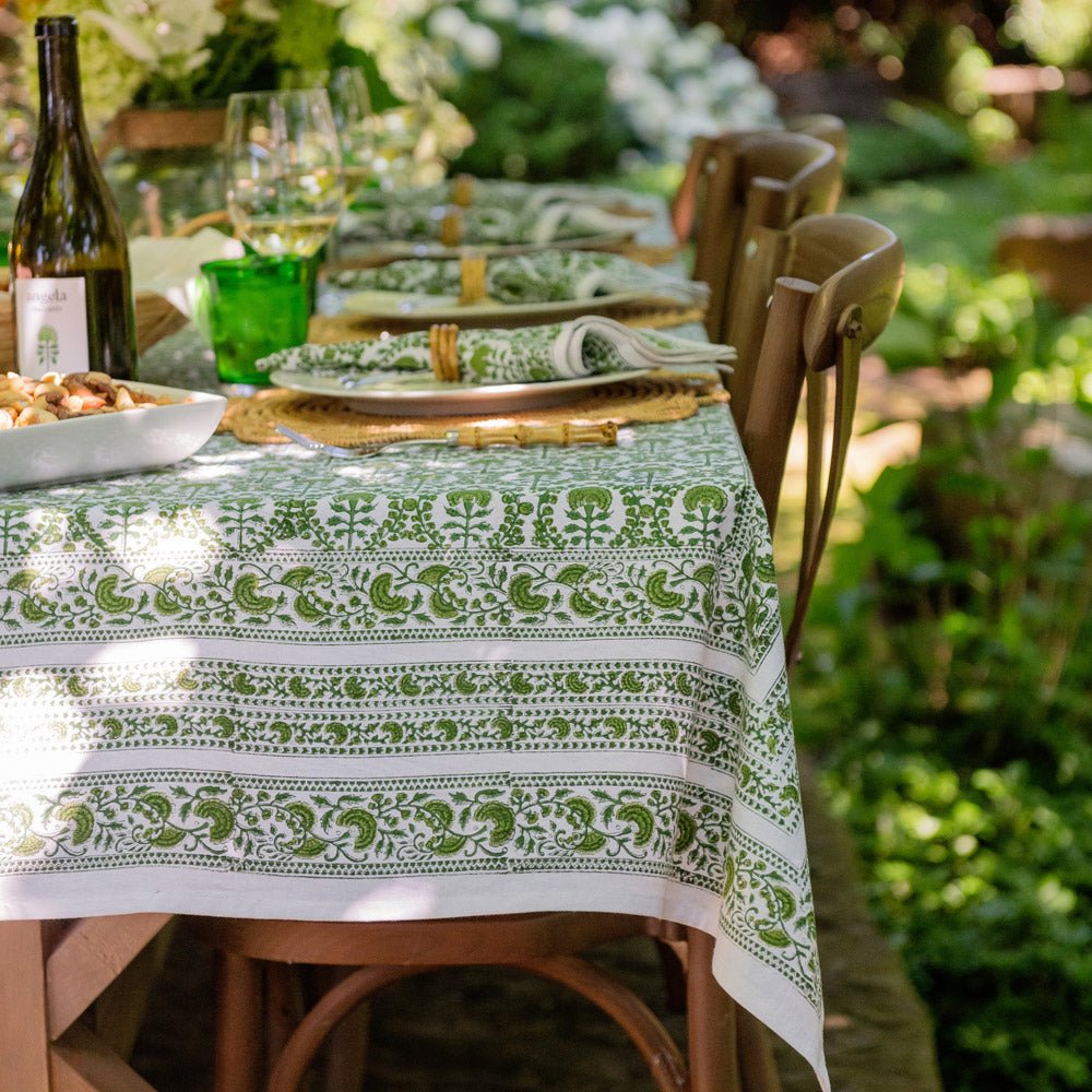 A green and white hand block printed tablecloth on a table with a garden backdrop.