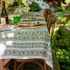 A green and white hand block printed tablecloth on a table with a garden backdrop.